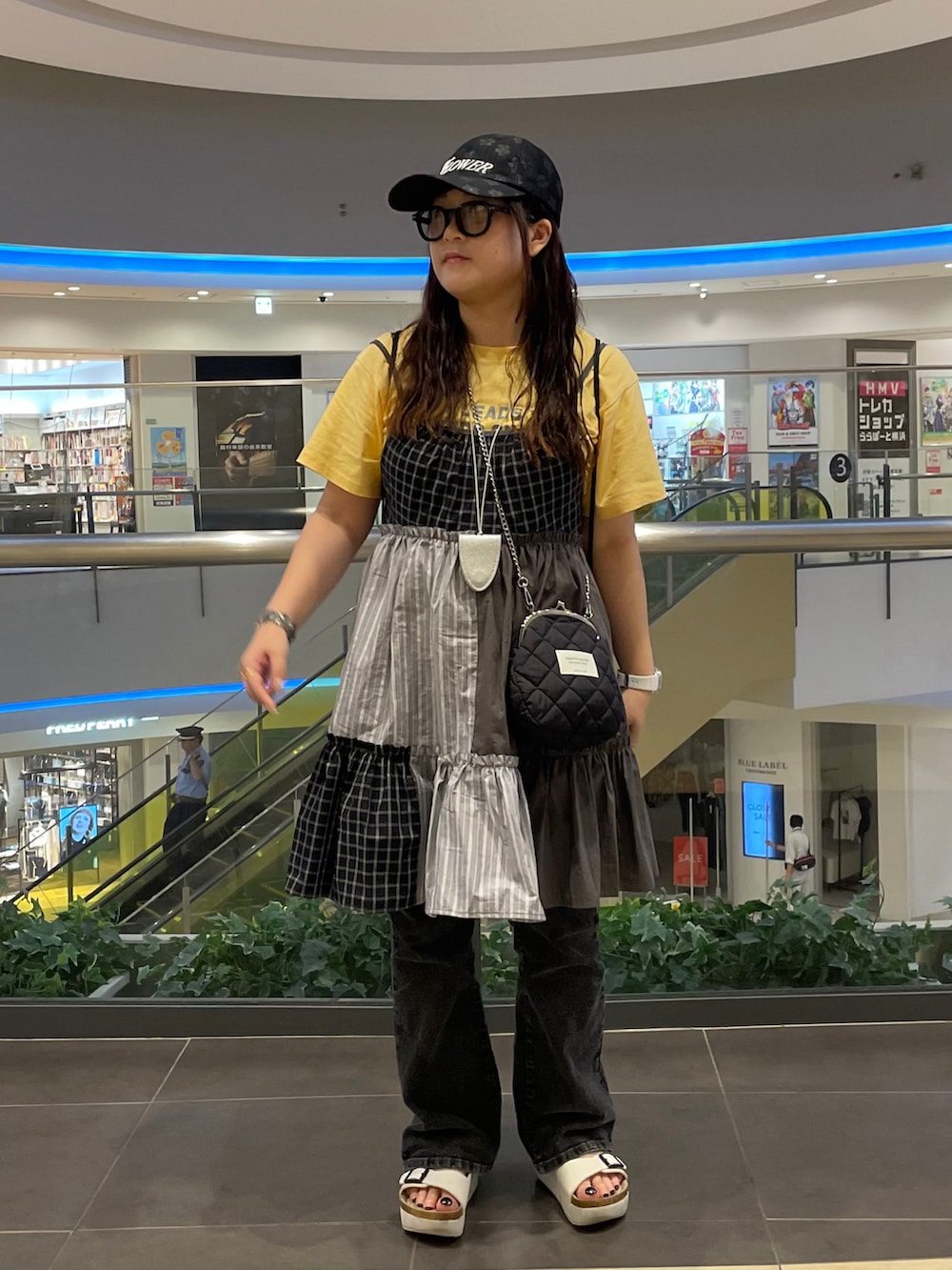 イエロー系のTシャツ/カットソー、ブラック系のワンピース、ブラック系のショルダーバッグを着用したレディースの夏コーディネートの2枚目の写真