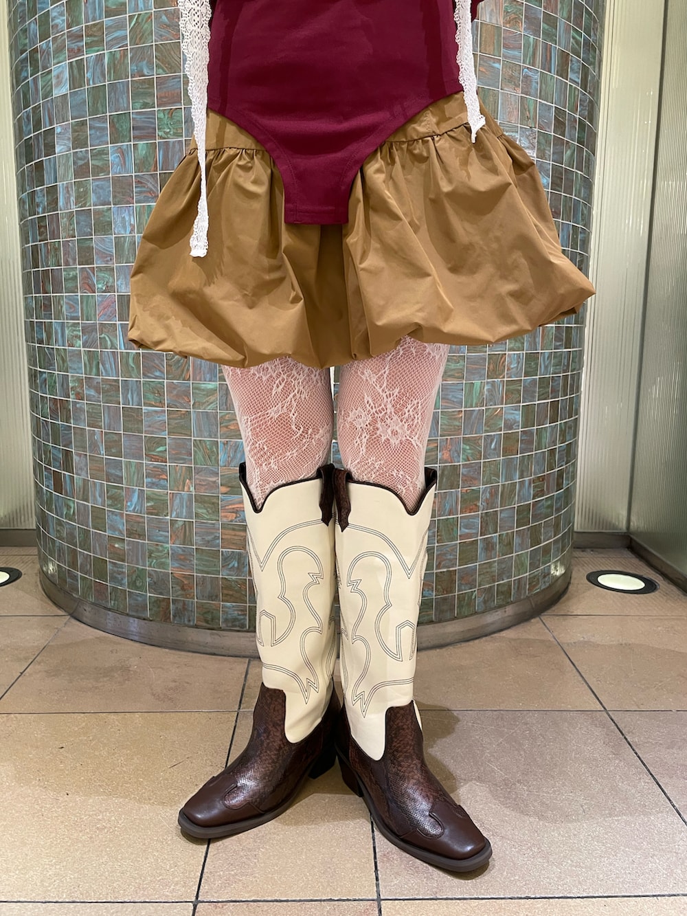 レッド系のTシャツ/カットソー、ブラウン系のワンピース、ブラウン系のブーツを着用したレディースの春コーディネートの3枚目の写真