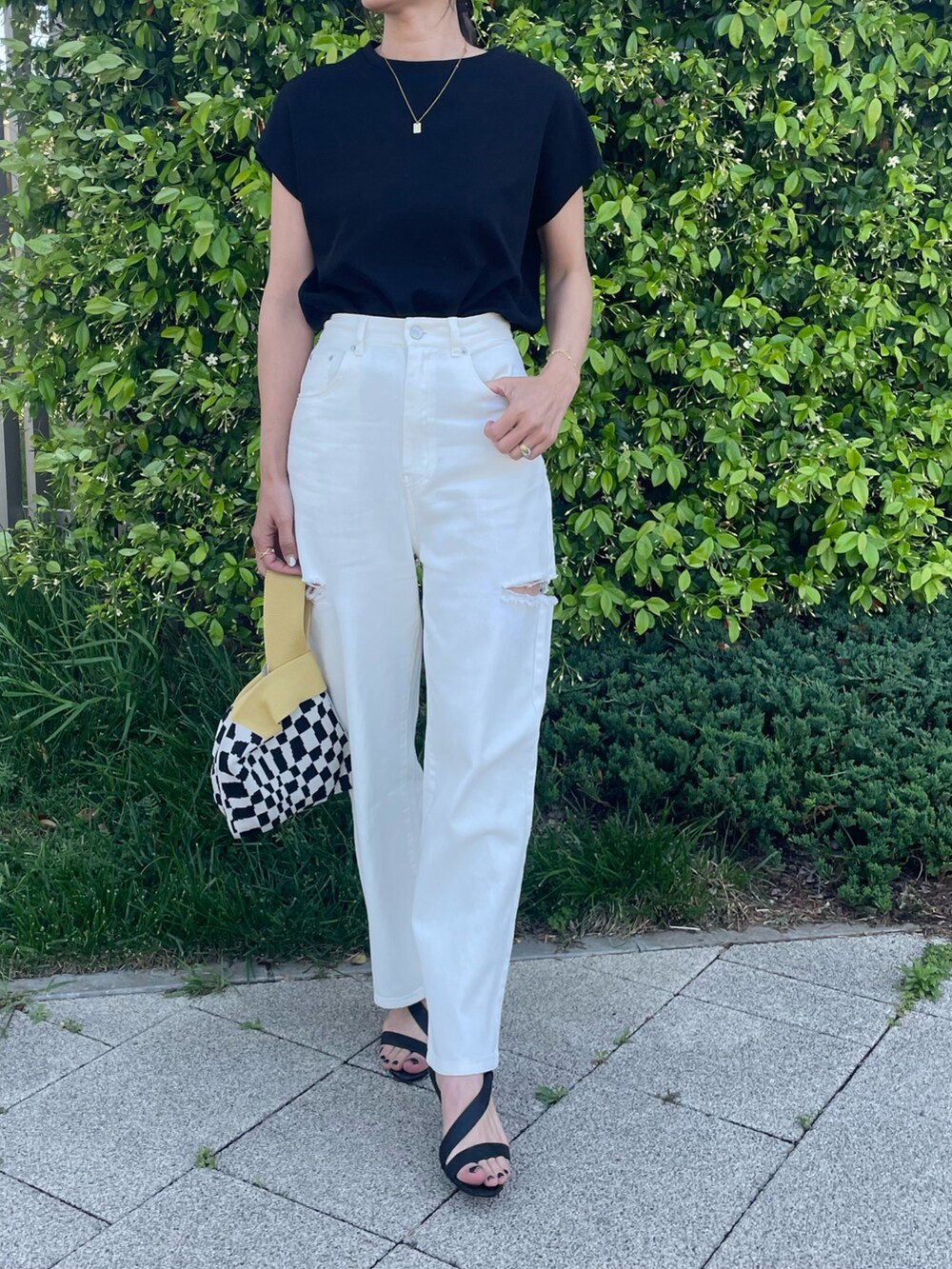 ブラック系のTシャツ/カットソー、ホワイト系のデニムパンツ、イエロー系のハンドバッグを着用したレディースの春コーディネートの4枚目の写真