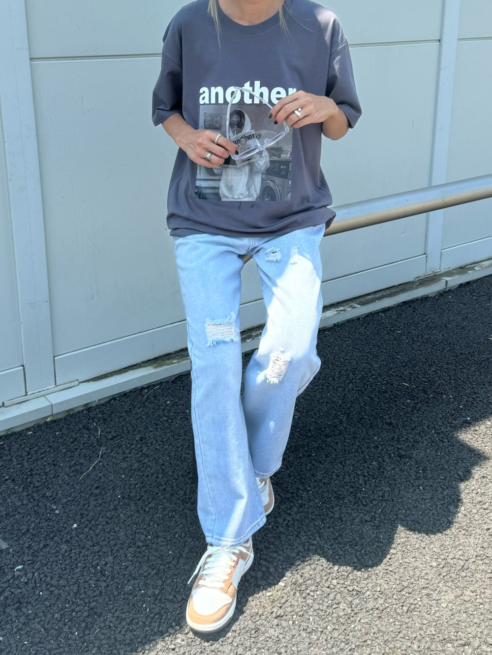 グレー系のTシャツ/カットソー、ブルー系のデニムパンツ、ブラウン系のスニーカーを着用したレディースの夏コーディネートの2枚目の写真