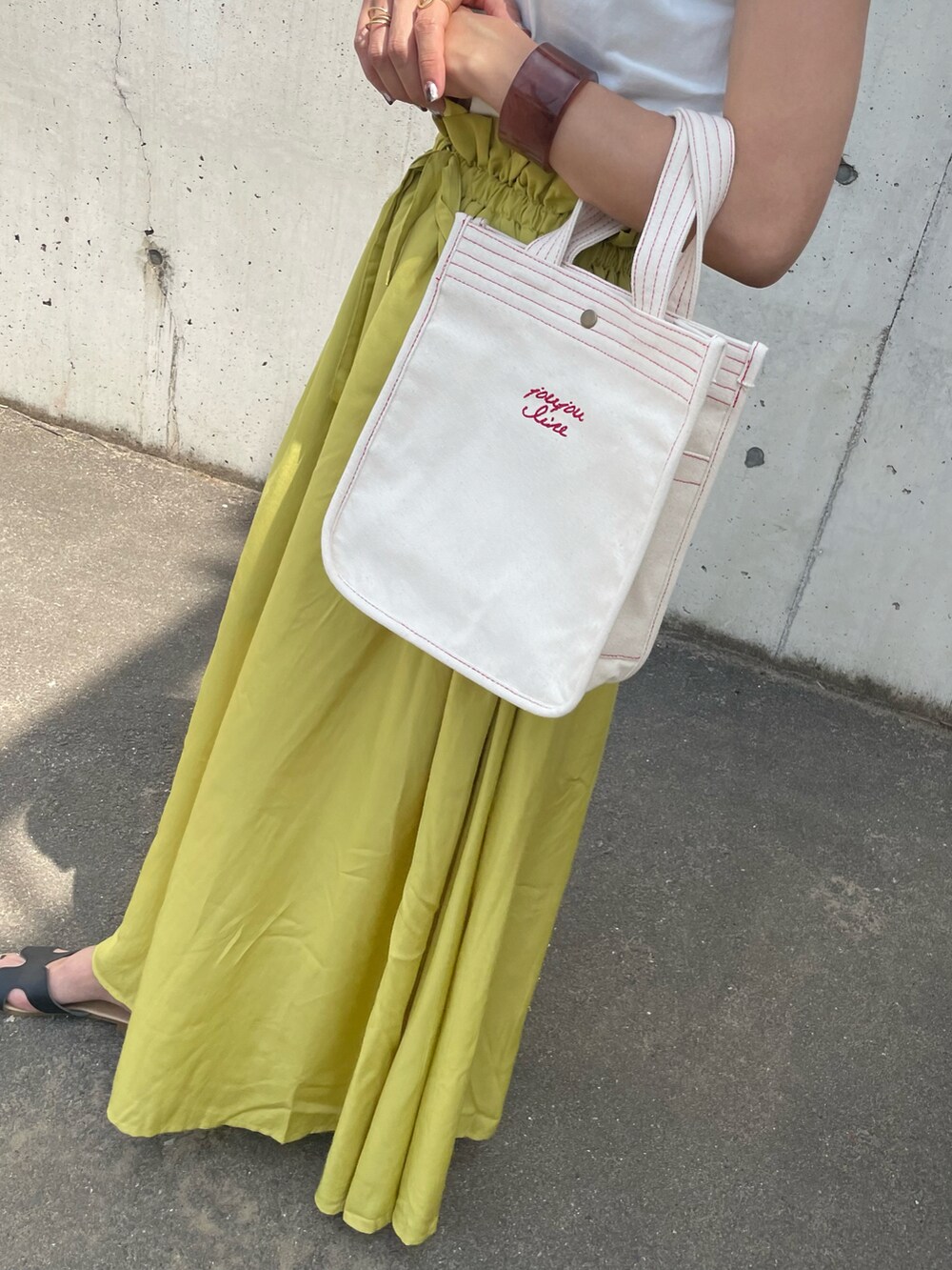 ホワイト系のTシャツ/カットソー、イエロー系のスカート、ホワイト系のトートバッグを着用したレディースの春コーディネートの4枚目の写真