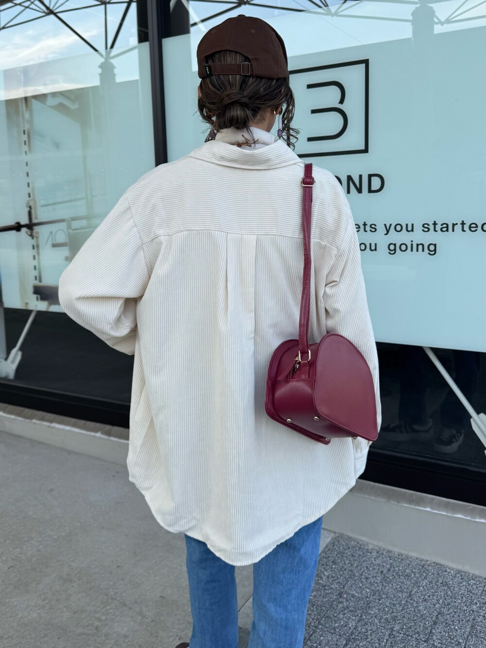 ホワイト系のニット/セーター、ブルー系のデニムパンツ、レッド系のショルダーバッグを着用したレディースの秋コーディネートの3枚目の写真