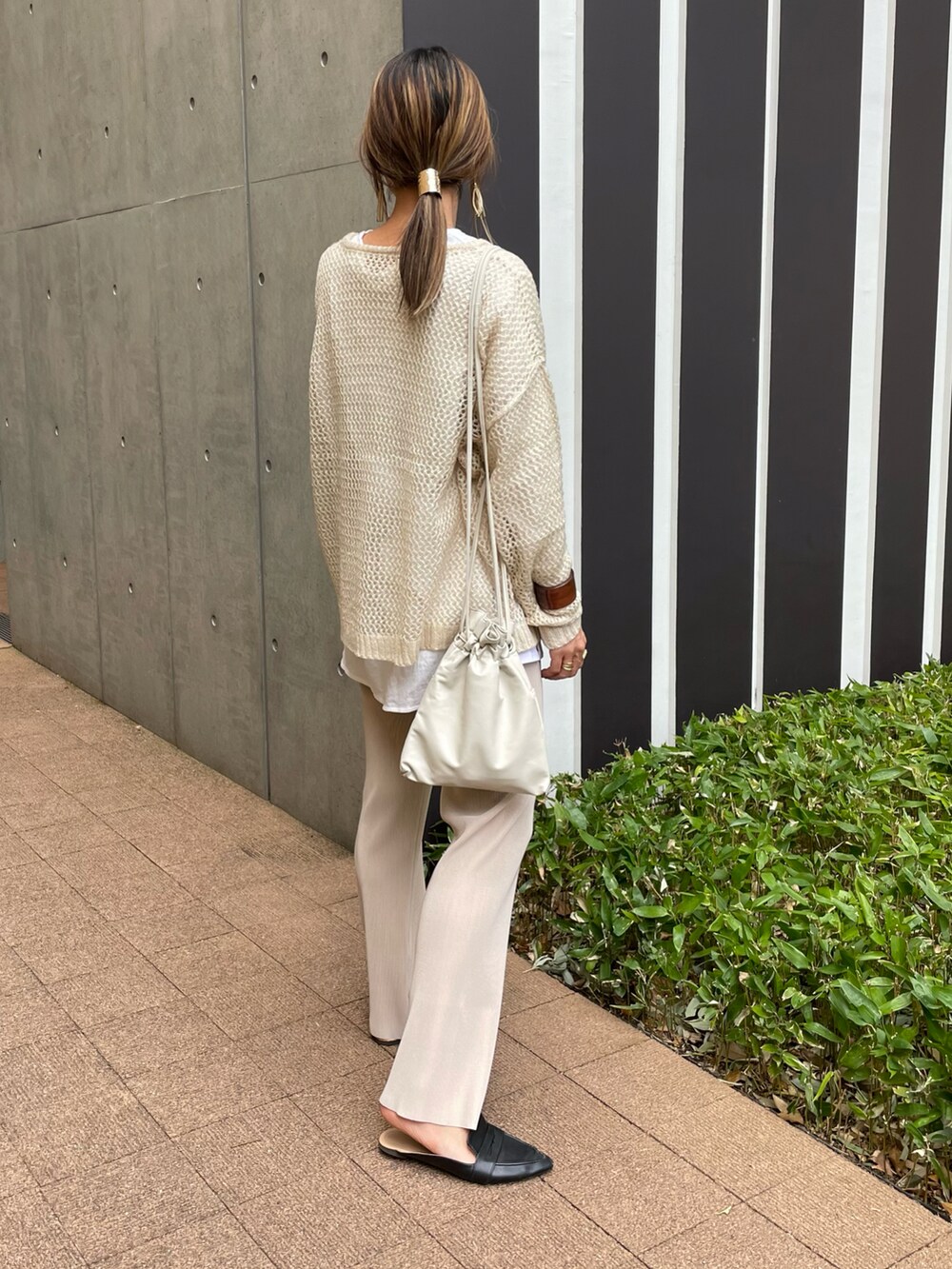 ベージュ系のニット/セーター、ホワイト系のTシャツ/カットソー、ホワイト系のショルダーバッグを着用したレディースの春コーディネートの4枚目の写真