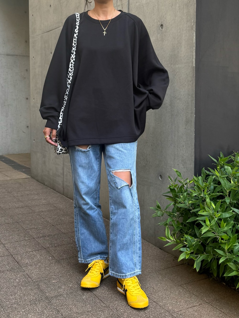 ブラック系のスウェット、ブルー系のデニムパンツ、ホワイト系のショルダーバッグを着用したレディースの秋コーディネートの2枚目の写真