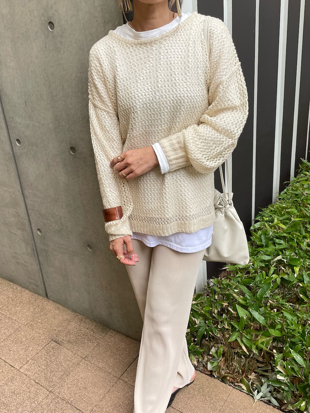 ベージュ系のニット/セーター、ホワイト系のTシャツ/カットソー、ホワイト系のショルダーバッグを着用したレディースの春コーディネートの5枚目の写真