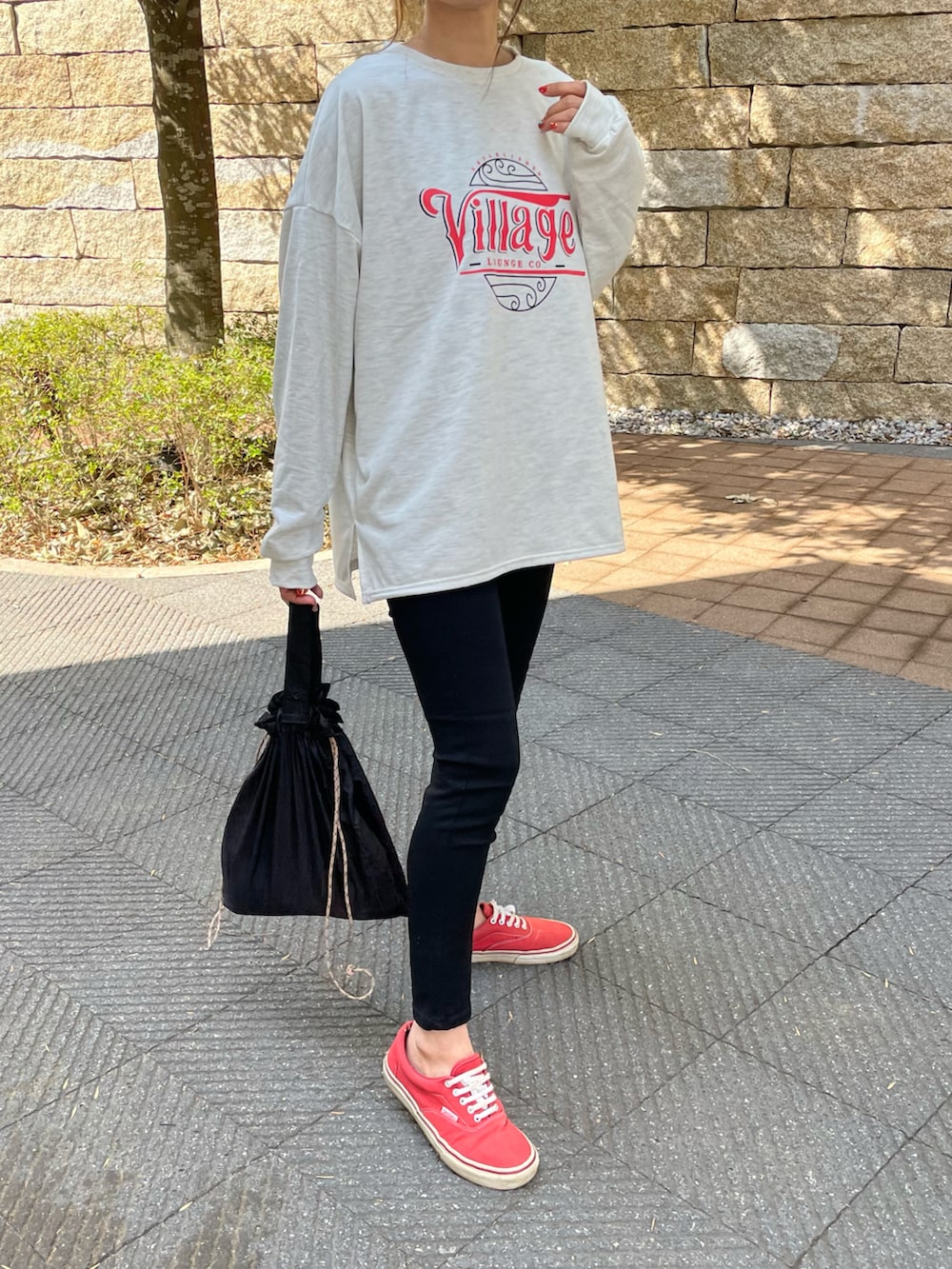 ブラック系のその他パンツ、グリーン系のエコバッグ/サブバッグ、レッド系のスニーカーを着用したレディースの春コーディネートの3枚目の写真