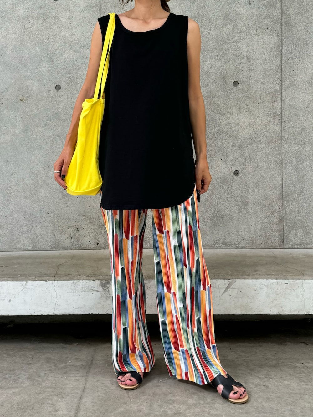 ブラック系のタンクトップ、その他のその他パンツ、イエロー系のトートバッグを着用したレディースの夏コーディネートの2枚目の写真