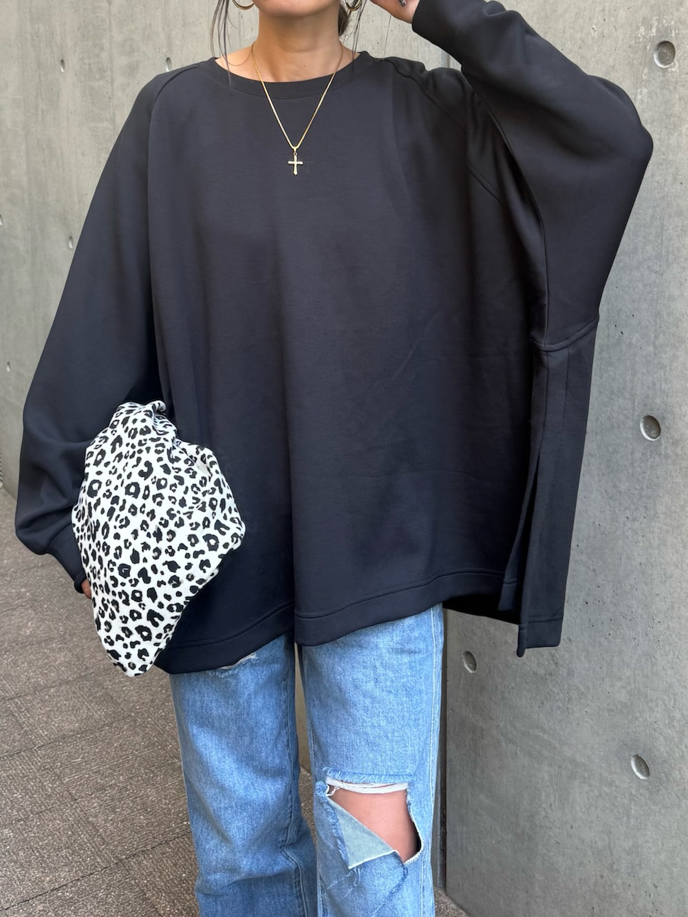 ブラック系のスウェット、ブルー系のデニムパンツ、ホワイト系のショルダーバッグを着用したレディースの秋コーディネートの4枚目の写真