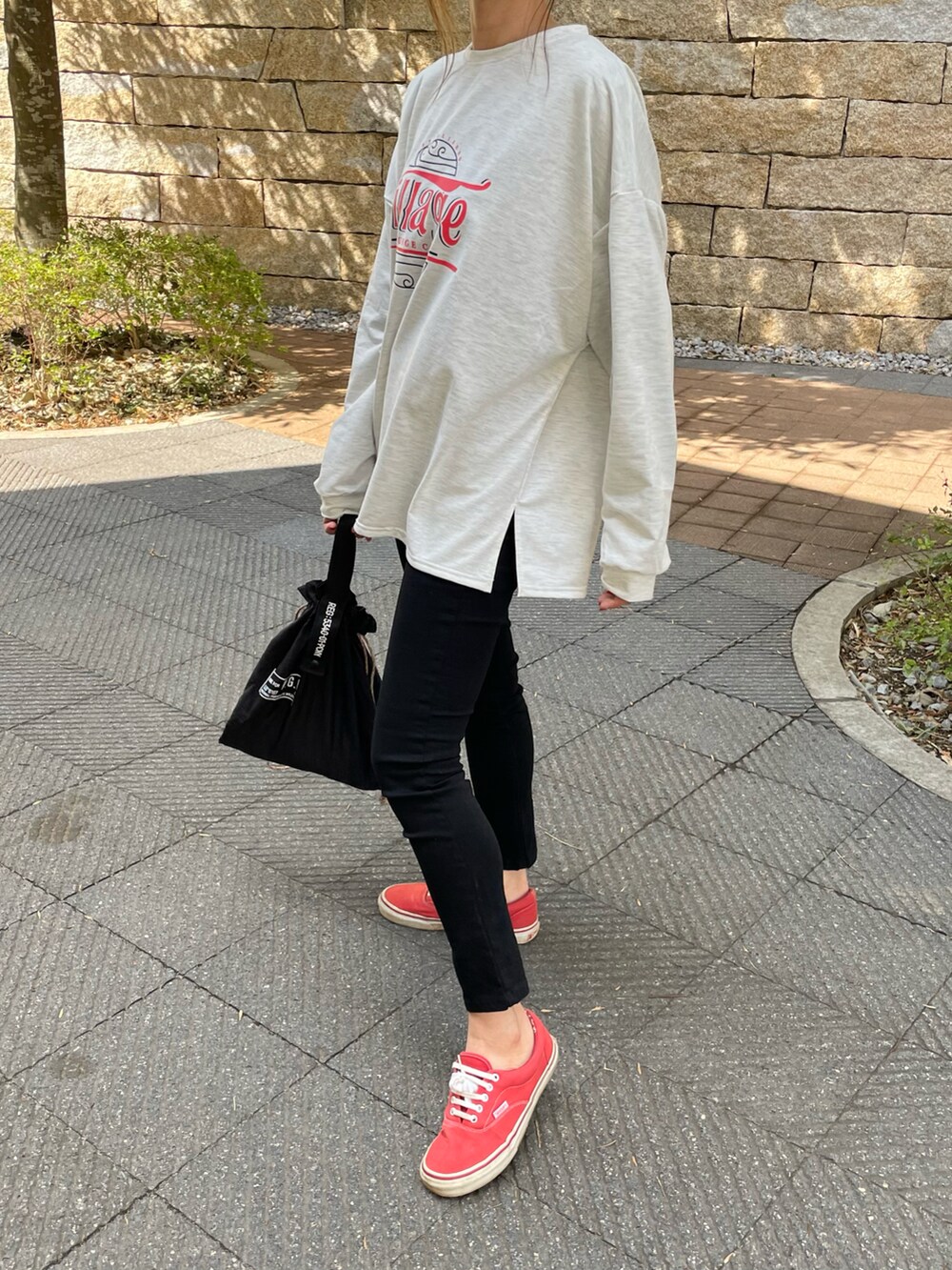ブラック系のその他パンツ、グリーン系のエコバッグ/サブバッグ、レッド系のスニーカーを着用したレディースの春コーディネートの5枚目の写真