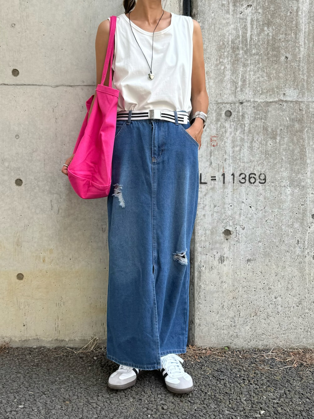 ブルー系のデニムスカート、ピンク系のトートバッグ、ホワイト系のスニーカーを着用したレディースの夏コーディネートの2枚目の写真