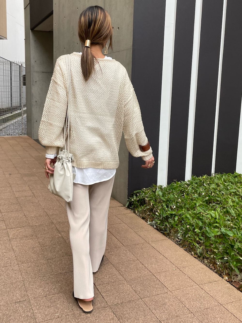 ベージュ系のニット/セーター、ホワイト系のTシャツ/カットソー、ホワイト系のショルダーバッグを着用したレディースの春コーディネートの3枚目の写真