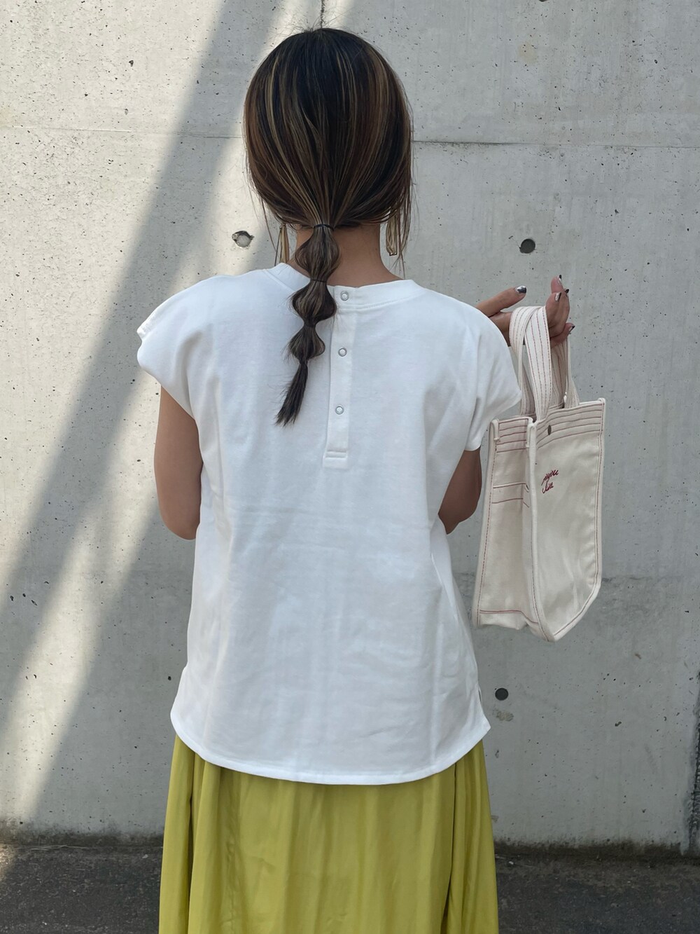 ホワイト系のTシャツ/カットソー、イエロー系のスカート、ホワイト系のトートバッグを着用したレディースの春コーディネートの5枚目の写真
