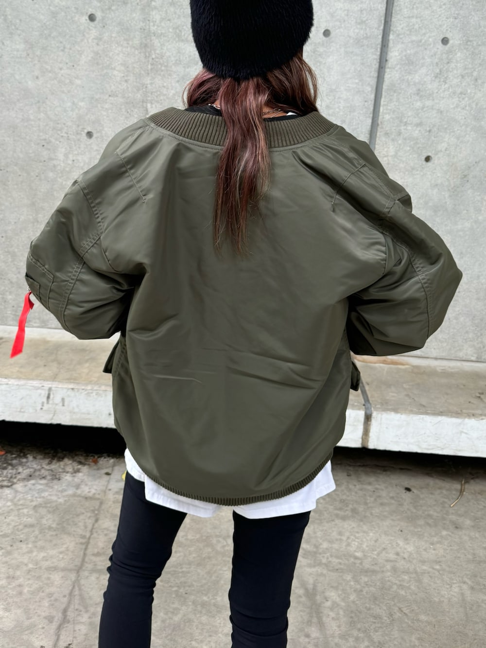 グリーン系のミリタリージャケット、ブラック系のスウェット、ホワイト系のその他パンツを着用したレディースの秋コーディネートの5枚目の写真