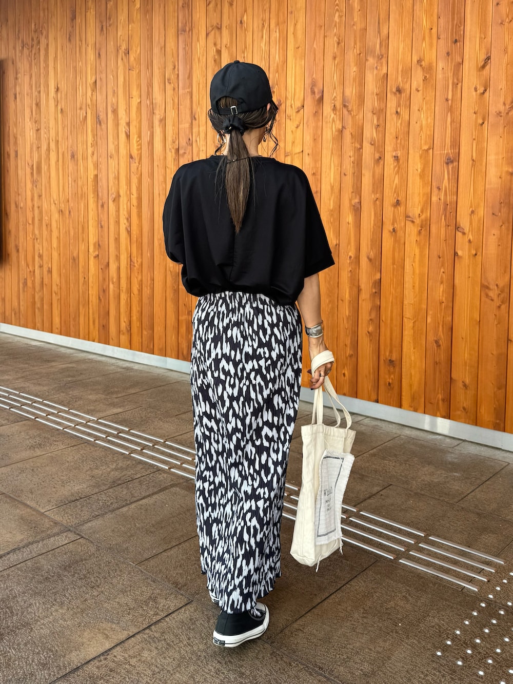 ブラック系のスニーカー、ブラック系のTシャツ/カットソー、ホワイト系のトートバッグを着用したレディースの夏コーディネートの3枚目の写真