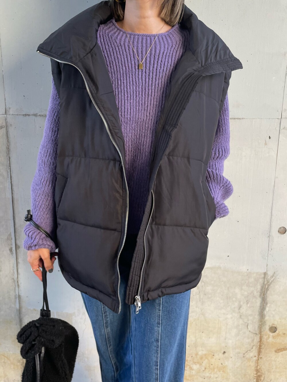 ブルー系のニット/セーター、ブラック系のダウンベスト、ブルー系のデニムパンツを着用したレディースの冬コーディネートの3枚目の写真