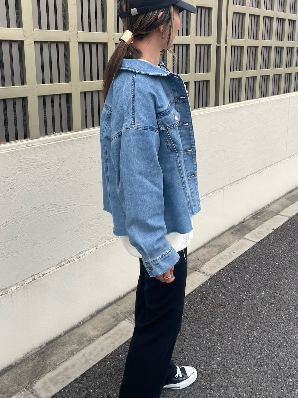 ブルー系のデニムジャケット、ブラック系のキャップを着用したレディースの春コーディネートの2枚目の写真