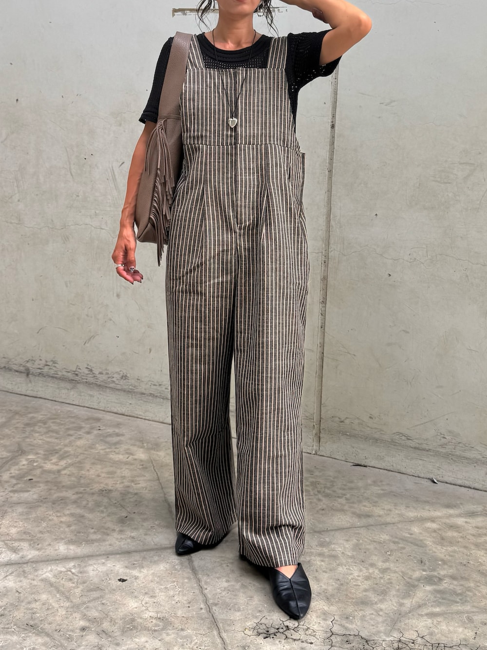 ブラック系のTシャツ/カットソー、ブラック系のサロペット/オーバーオール、ベージュ系のショルダーバッグを着用したレディースの秋コーディネートの2枚目の写真