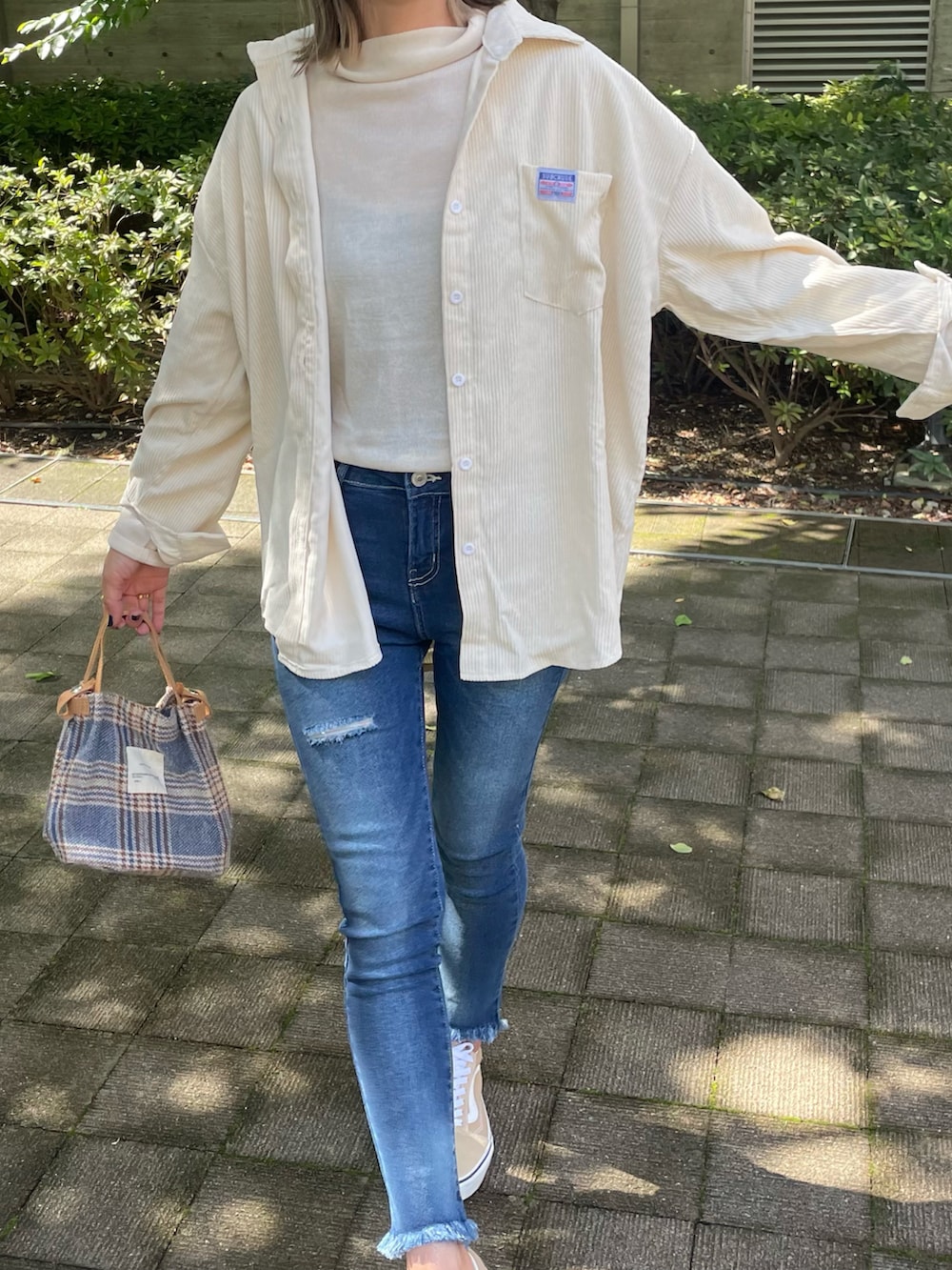 ホワイト系のシャツ/ブラウス、ホワイト系のニット/セーター、ブルー系のデニムパンツを着用したレディースの秋コーディネートの3枚目の写真