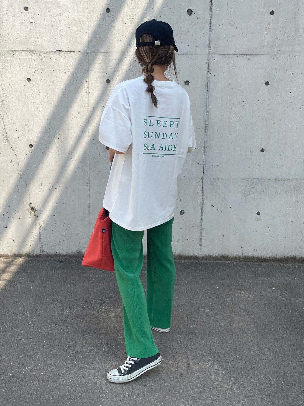 グリーン系のTシャツ/カットソー、オレンジ系のトートバッグ、ブラック系のスニーカーを着用したレディースの春コーディネートの4枚目の写真