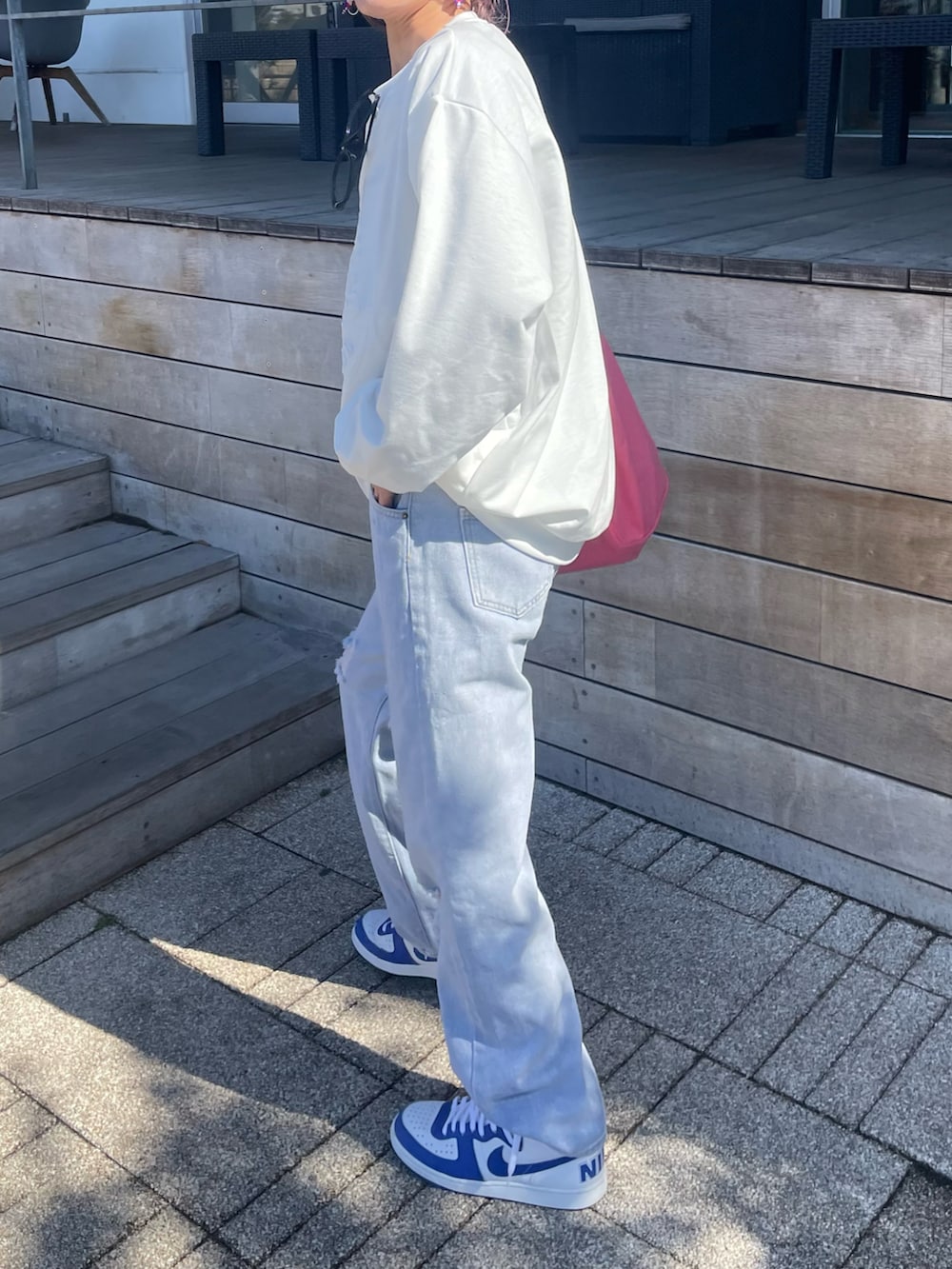 ホワイト系のスウェット、ブルー系のデニムパンツ、ピンク系のトートバッグを着用したレディースの春コーディネートの2枚目の写真