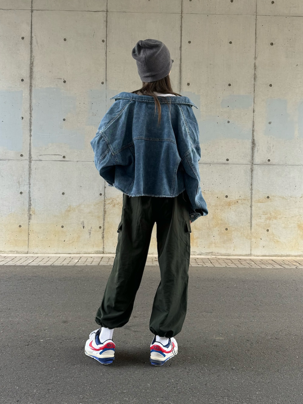 ブルー系のデニムジャケット、グリーン系のカーゴパンツ、ホワイト系のスニーカーを着用したレディースの春コーディネートの3枚目の写真