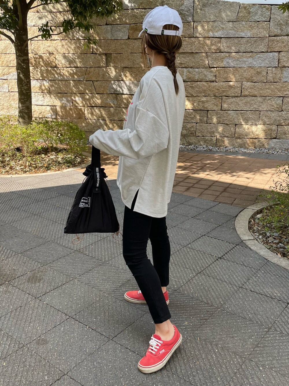 ブラック系のその他パンツ、グリーン系のエコバッグ/サブバッグ、レッド系のスニーカーを着用したレディースの春コーディネートの2枚目の写真