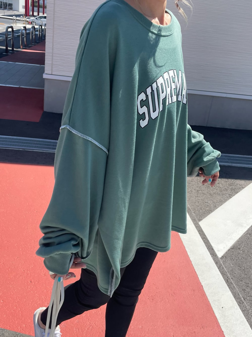 グリーン系のスウェット、ブラック系のその他パンツ、ホワイト系のショルダーバッグを着用したレディースの春コーディネートの4枚目の写真