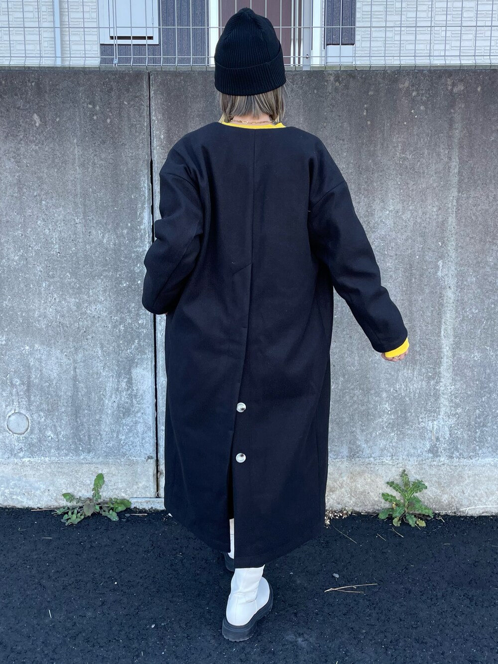 イエロー系のスウェット、ブラック系のノーカラーコート、ブラック系のその他パンツを着用したレディースの秋コーディネートの3枚目の写真