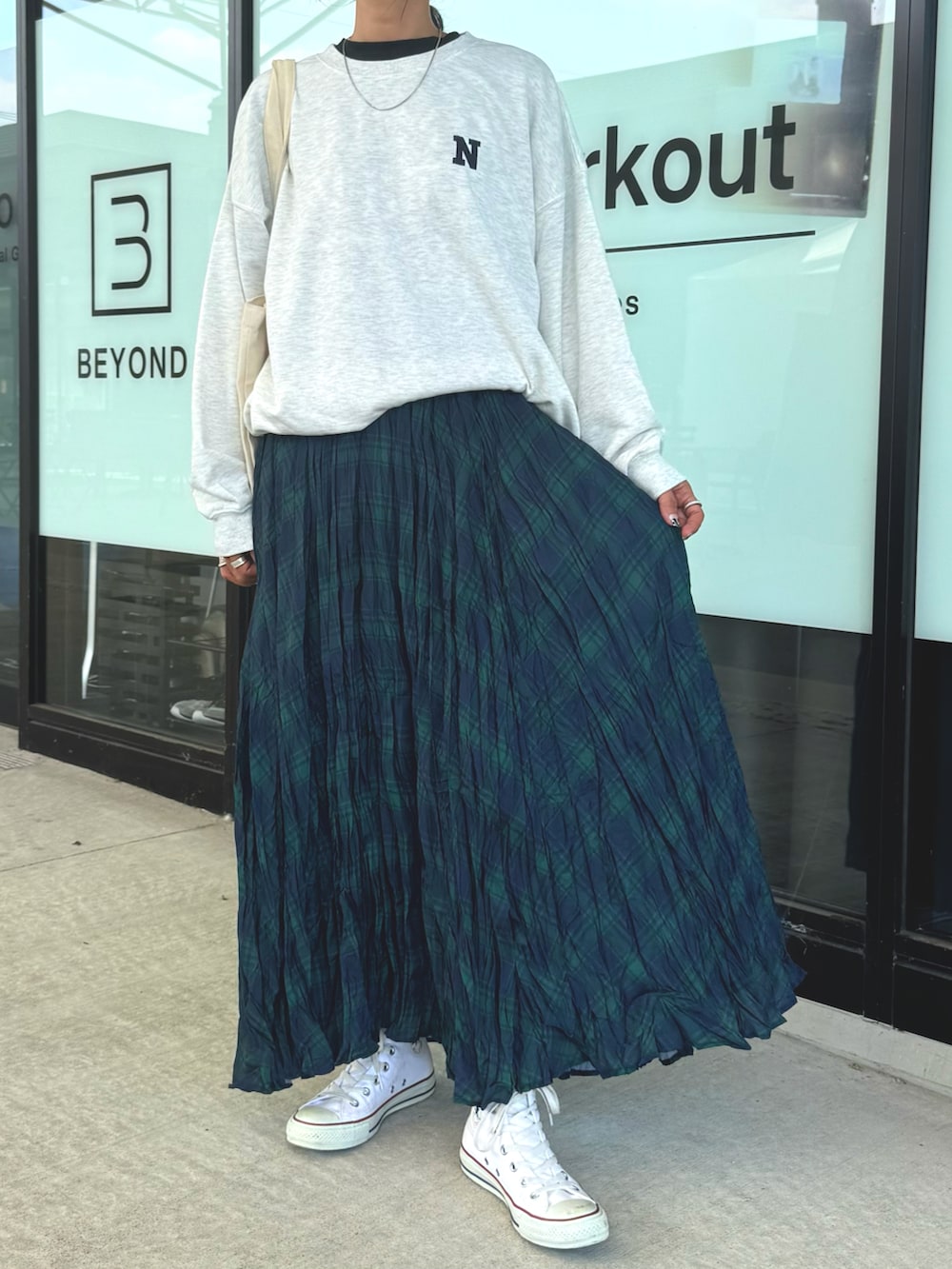 ホワイト系のスニーカー、ホワイト系のスウェット、グリーン系のスカートを着用したレディースの秋コーディネートの2枚目の写真