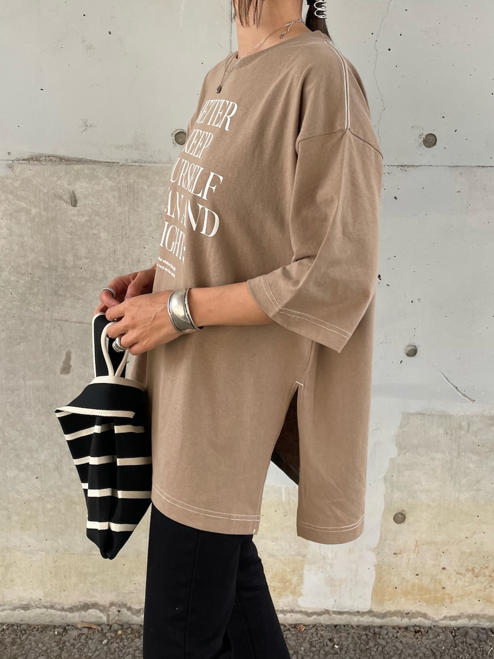 ベージュ系のTシャツ/カットソー、ブラック系のデニムパンツ、ブラック系のハンドバッグを着用したレディースの春コーディネートの5枚目の写真