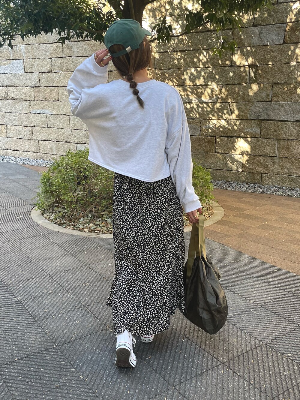 グリーン系のスウェット、ブラック系のスカート、ホワイト系のスニーカーを着用したレディースの冬コーディネートの3枚目の写真