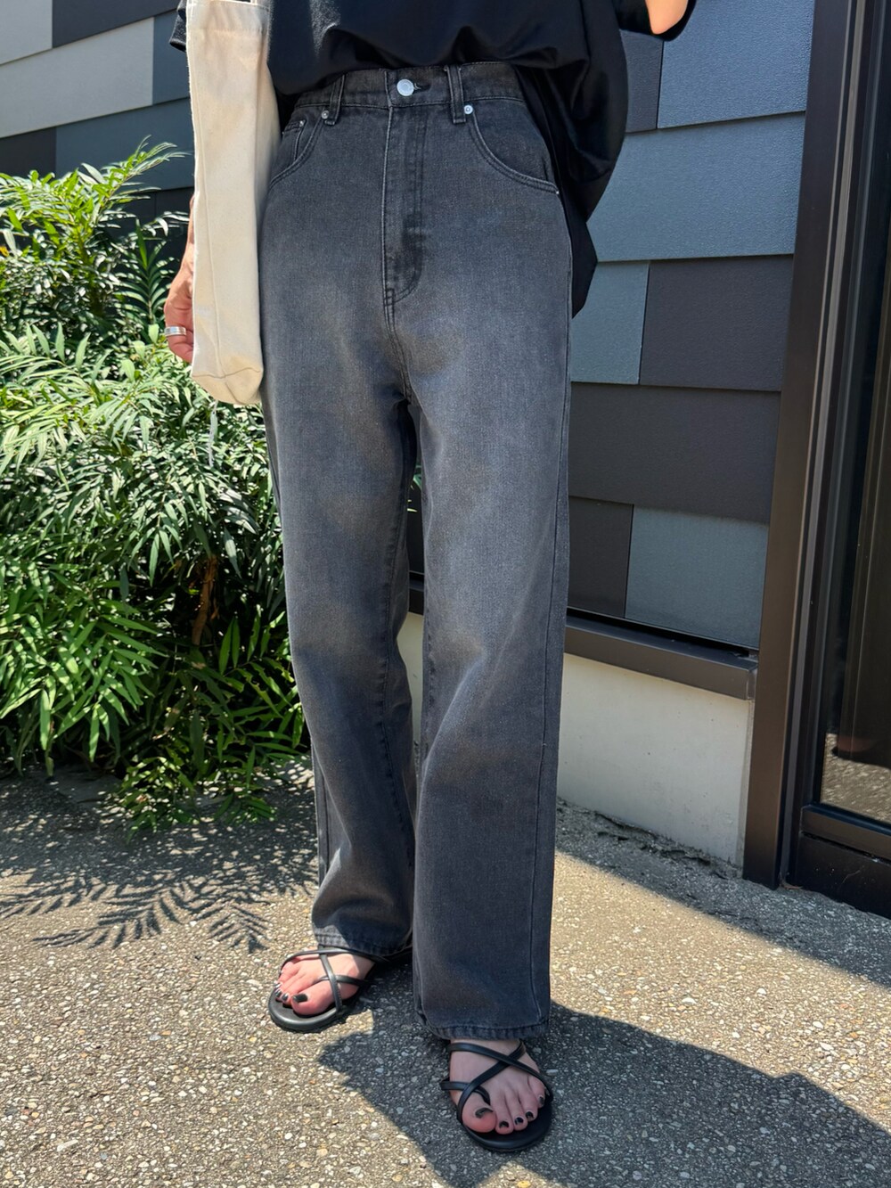 ブラック系のTシャツ/カットソー、ブラック系のデニムパンツ、ホワイト系のトートバッグを着用したレディースの夏コーディネートの4枚目の写真
