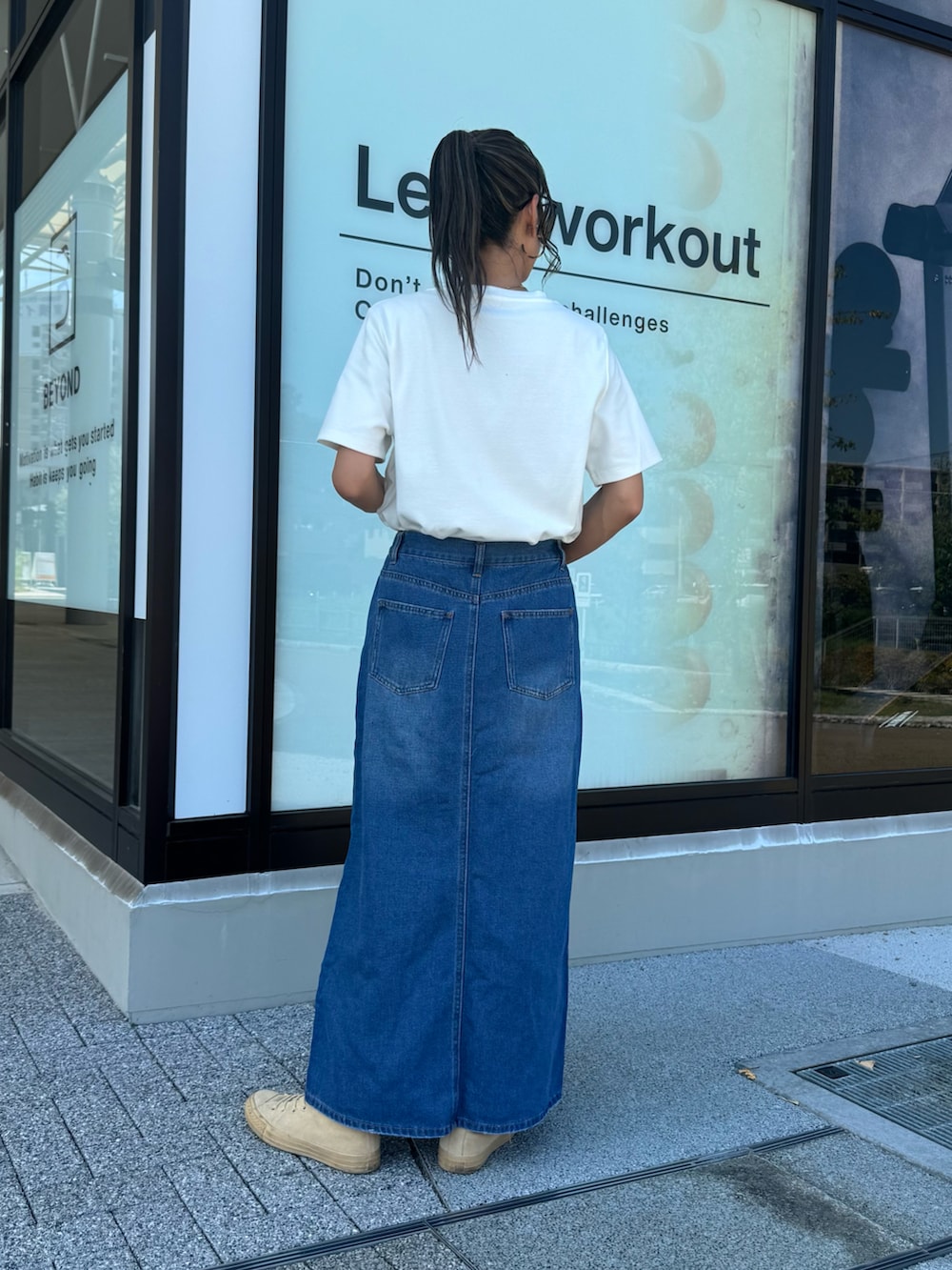 ホワイト系のTシャツ/カットソー、ブルー系のデニムスカート、ベージュ系のスニーカーを着用したレディースの秋コーディネートの4枚目の写真