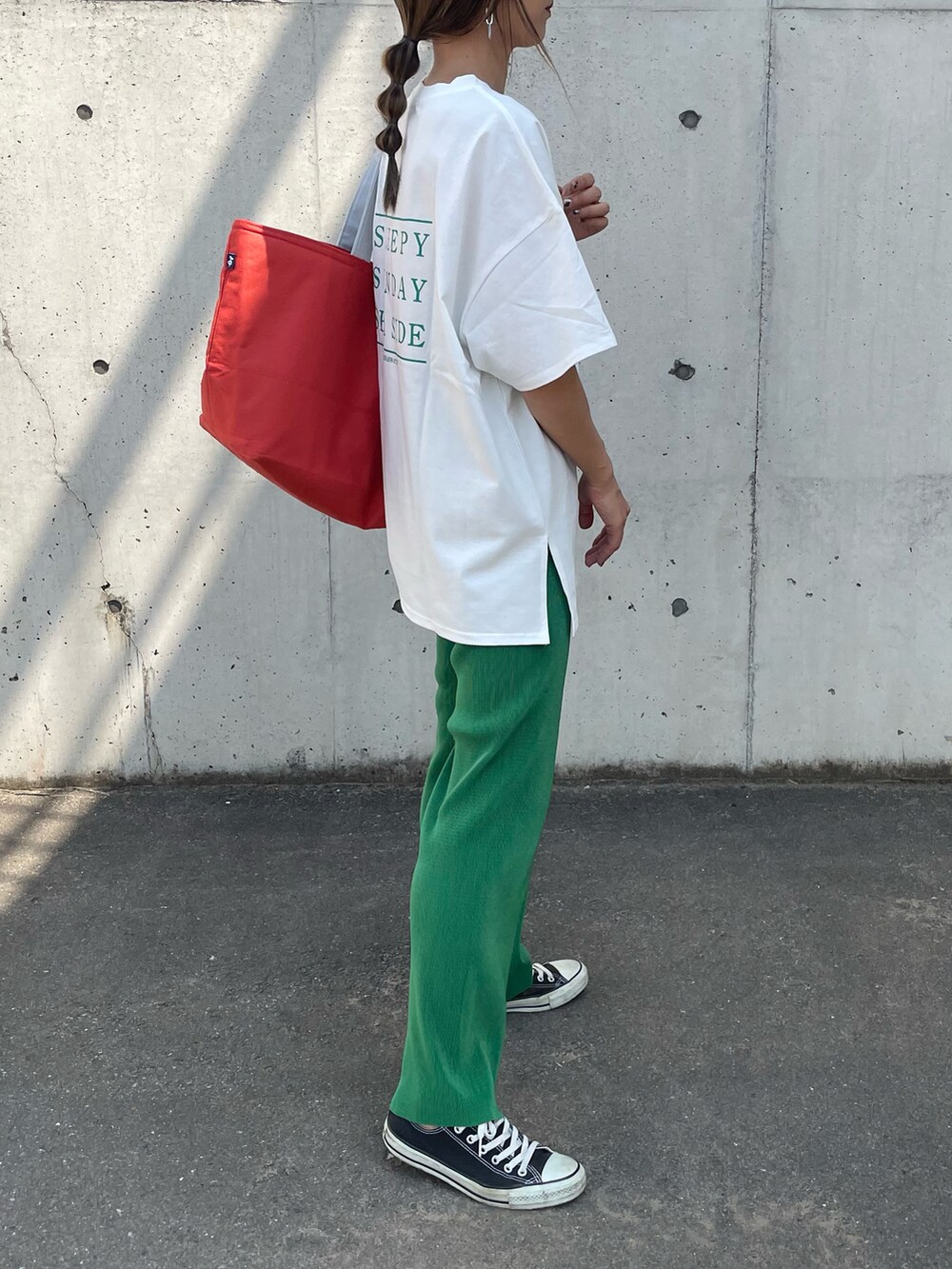 グリーン系のTシャツ/カットソー、オレンジ系のトートバッグ、ブラック系のスニーカーを着用したレディースの春コーディネートの3枚目の写真