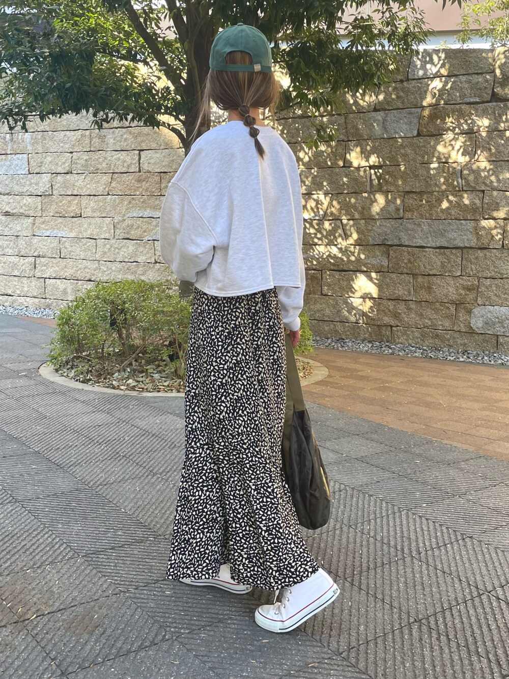 グリーン系のスウェット、ブラック系のスカート、ホワイト系のスニーカーを着用したレディースの冬コーディネートの4枚目の写真