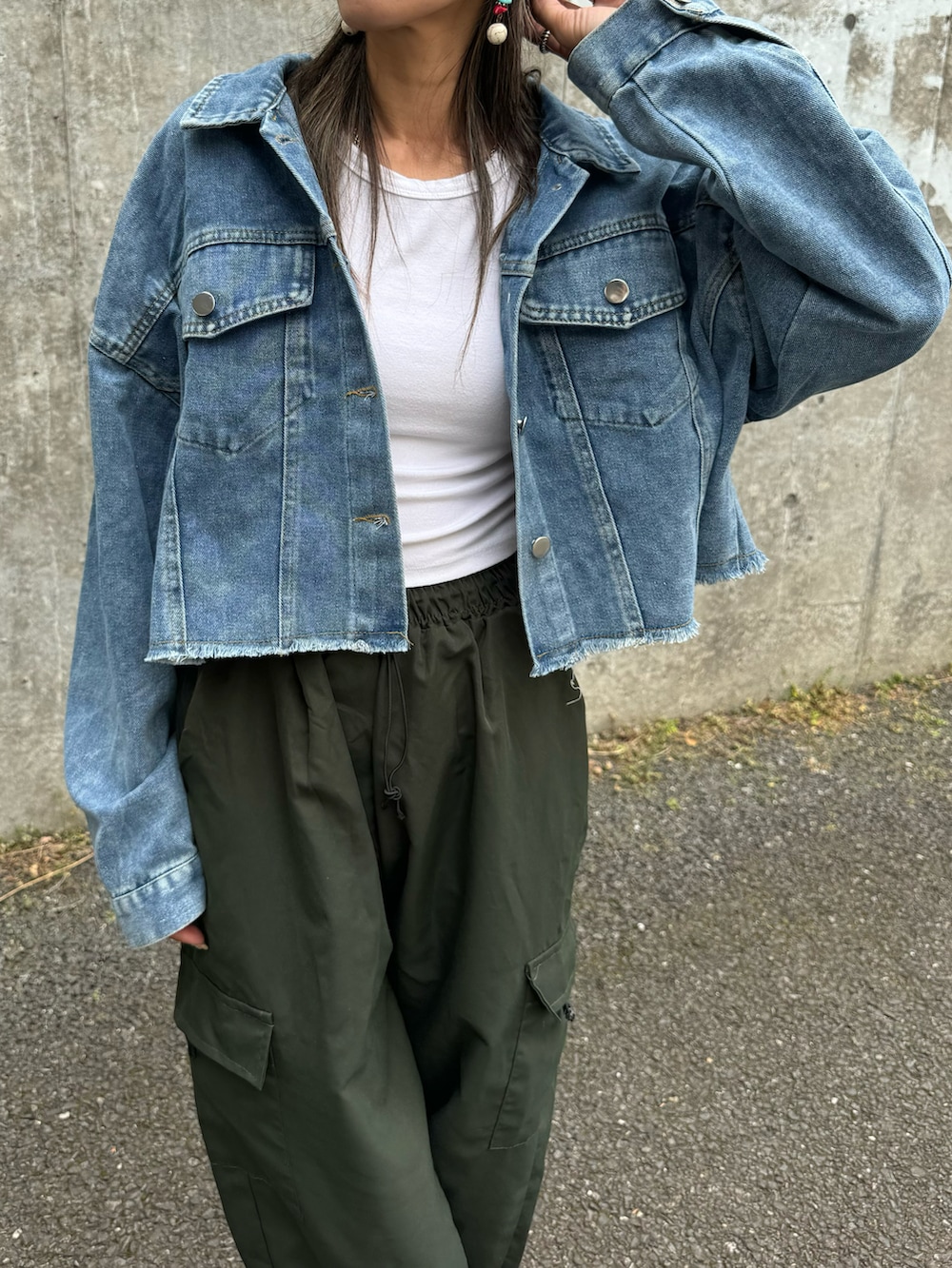 ブルー系のデニムジャケット、グリーン系のカーゴパンツ、ホワイト系のスニーカーを着用したレディースの春コーディネートの4枚目の写真