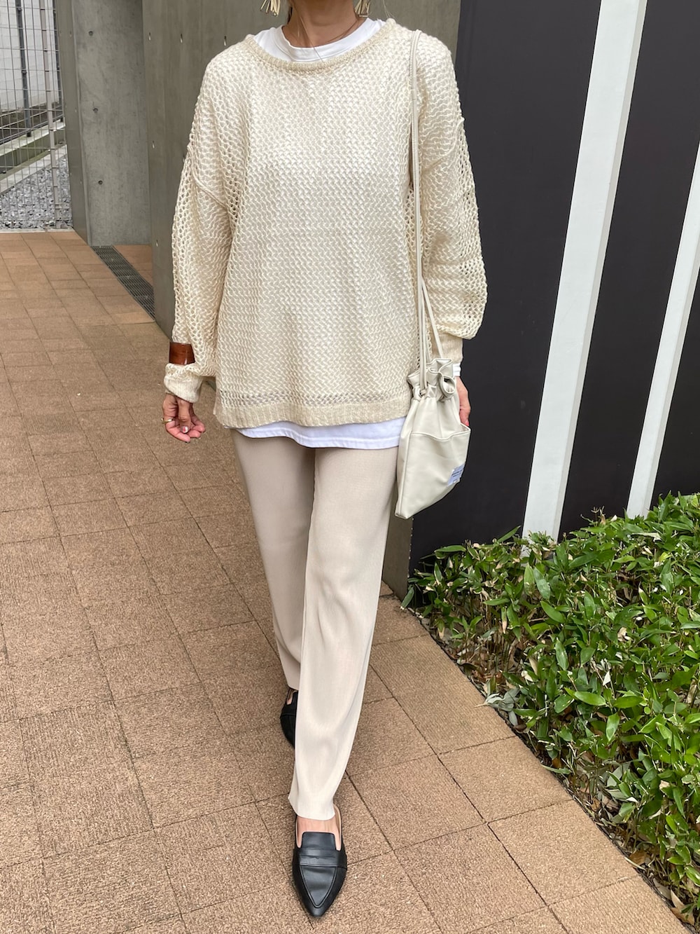 ベージュ系のニット/セーター、ホワイト系のTシャツ/カットソー、ホワイト系のショルダーバッグを着用したレディースの春コーディネートの2枚目の写真