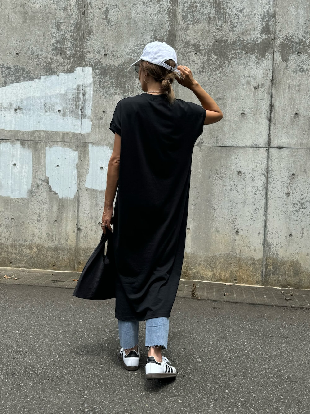 ブラック系のワンピース、ブルー系のデニムパンツ、ホワイト系のスニーカーを着用したレディースの夏コーディネートの3枚目の写真