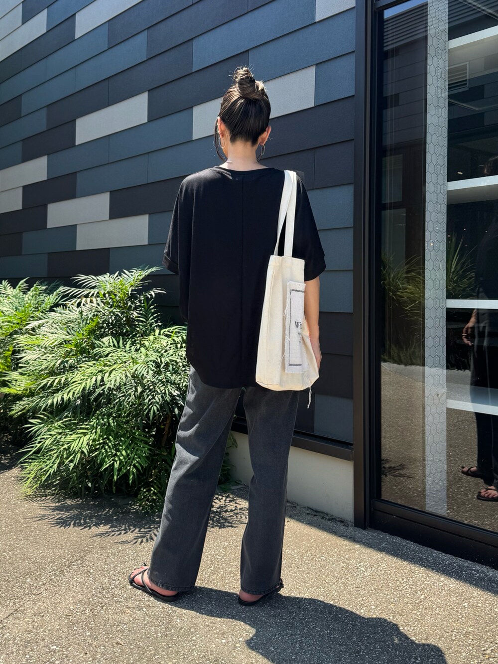 ブラック系のTシャツ/カットソー、ブラック系のデニムパンツ、ホワイト系のトートバッグを着用したレディースの夏コーディネートの3枚目の写真