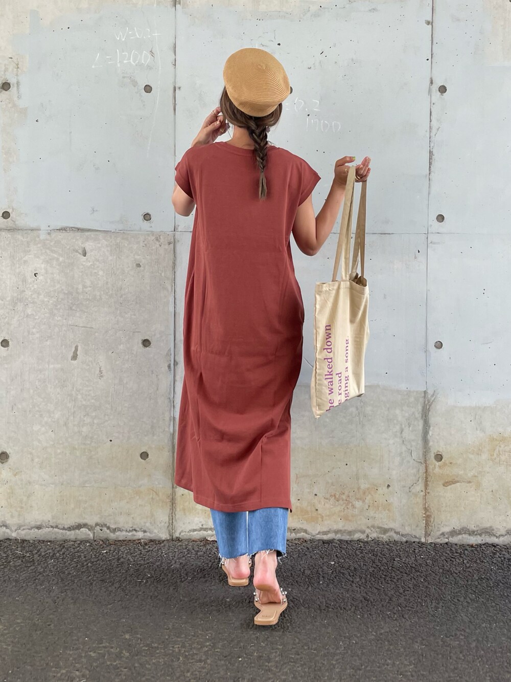 オレンジ系のワンピース、ベージュ系のトートバッグ、ブルー系のデニムパンツを着用したレディースの夏コーディネートの3枚目の写真