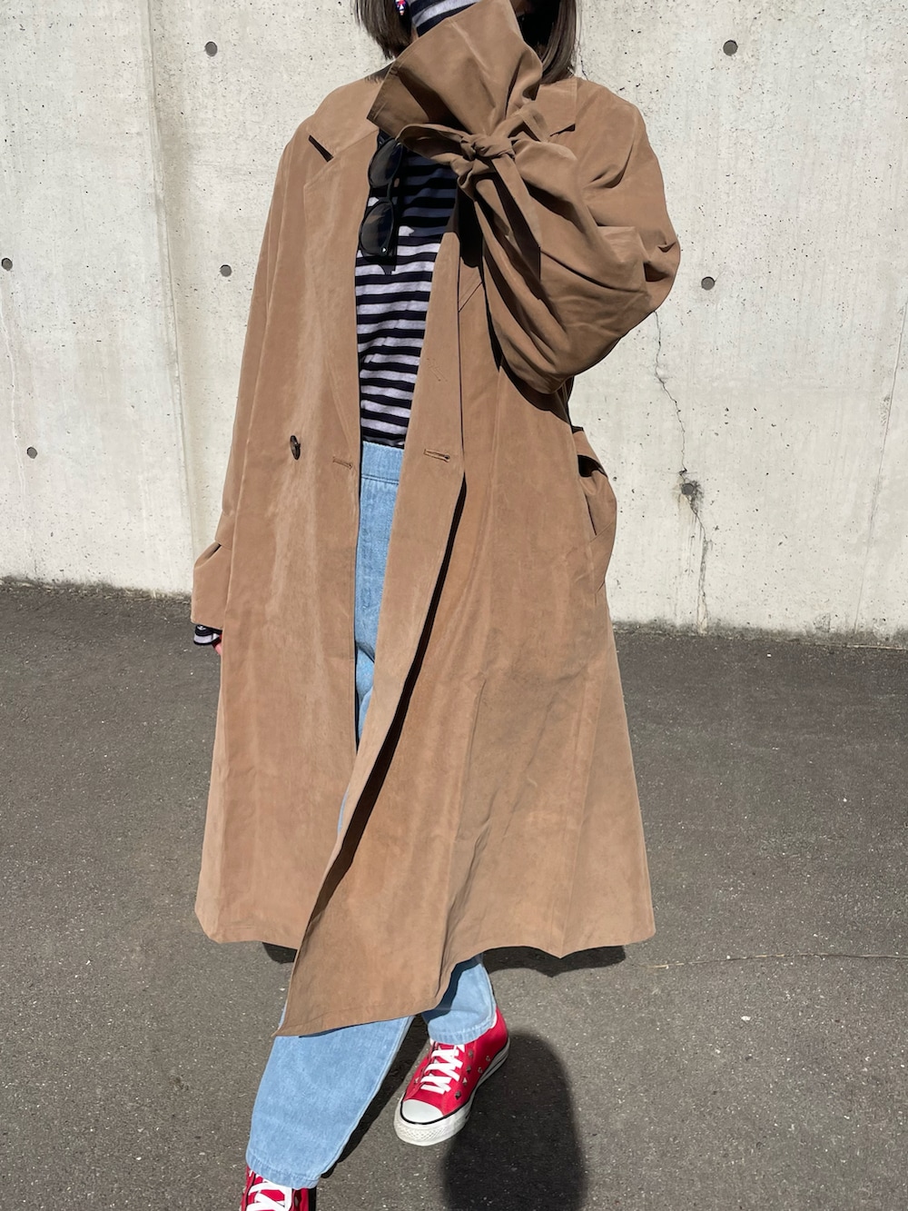 ブラック系のTシャツ/カットソー、ブラウン系のトレンチコート、ブルー系のデニムパンツを着用したレディースの冬コーディネートの5枚目の写真