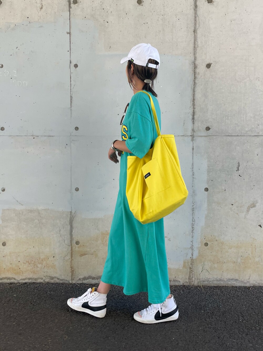 ブルー系のワンピース、イエロー系のトートバッグ、ホワイト系のスニーカーを着用したレディースの春コーディネートの2枚目の写真
