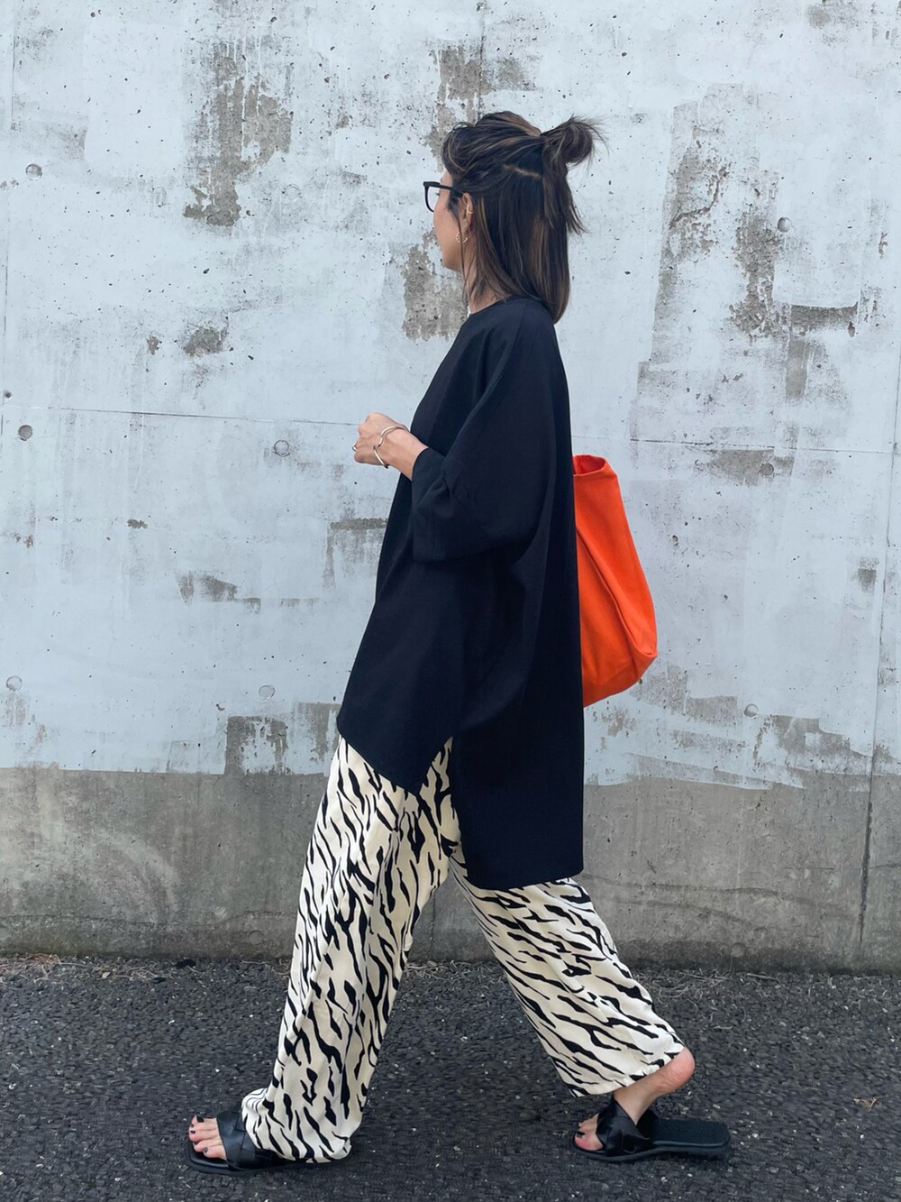 ブラック系のTシャツ/カットソー、ホワイト系のその他パンツ、オレンジ系のトートバッグを着用したレディースの春コーディネートの4枚目の写真