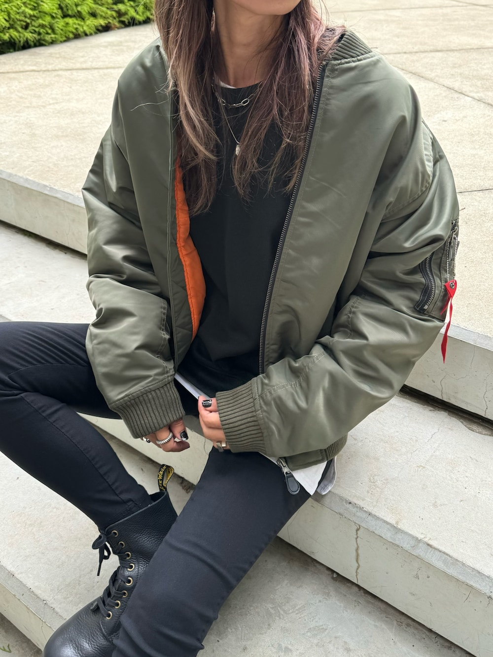 グリーン系のミリタリージャケット、ブラック系のスウェット、ホワイト系のその他パンツを着用したレディースの秋コーディネートの4枚目の写真