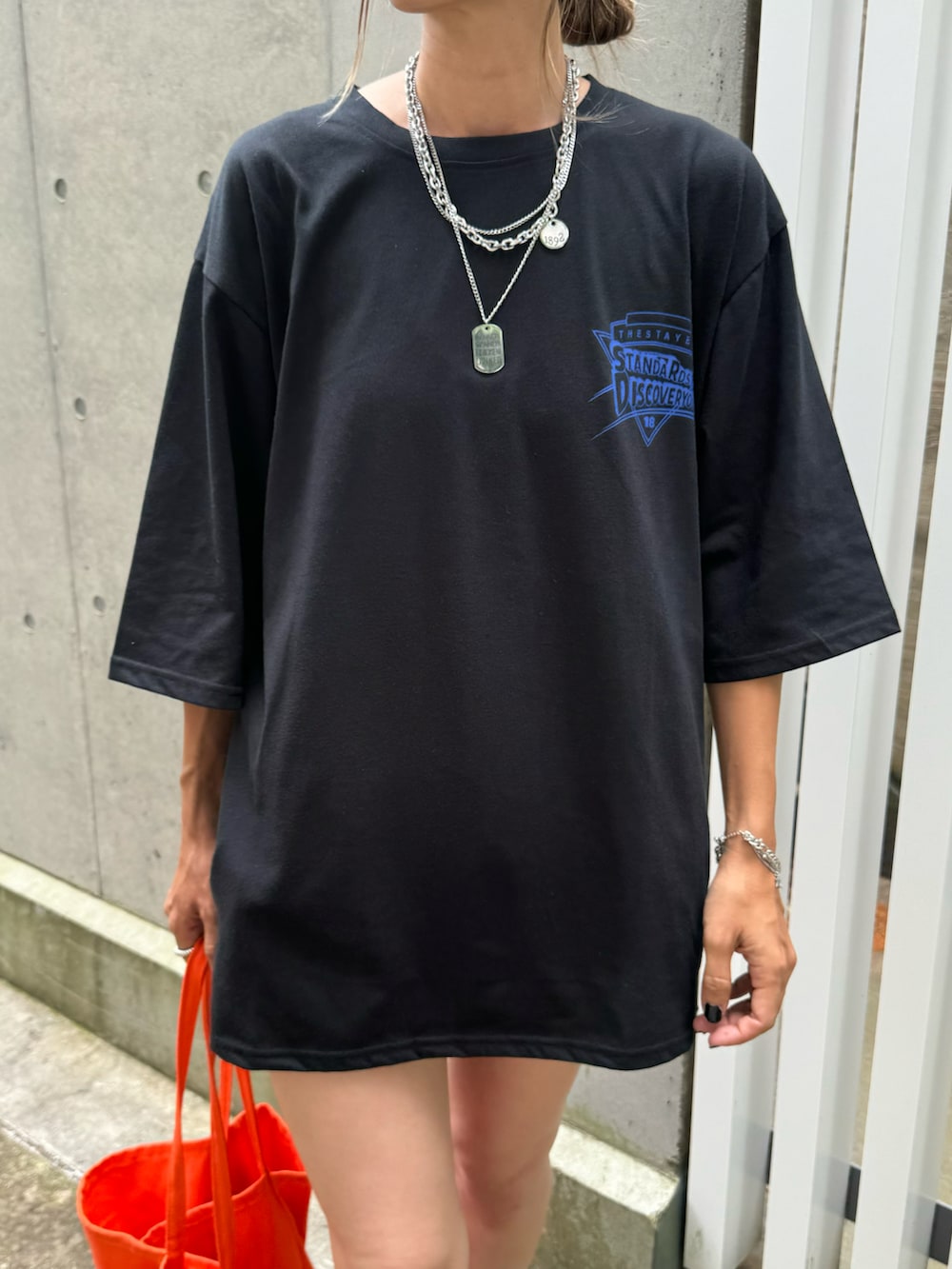ブラック系のTシャツ/カットソー、オレンジ系のトートバッグ、ブラック系のスニーカーを着用したレディースの夏コーディネートの3枚目の写真