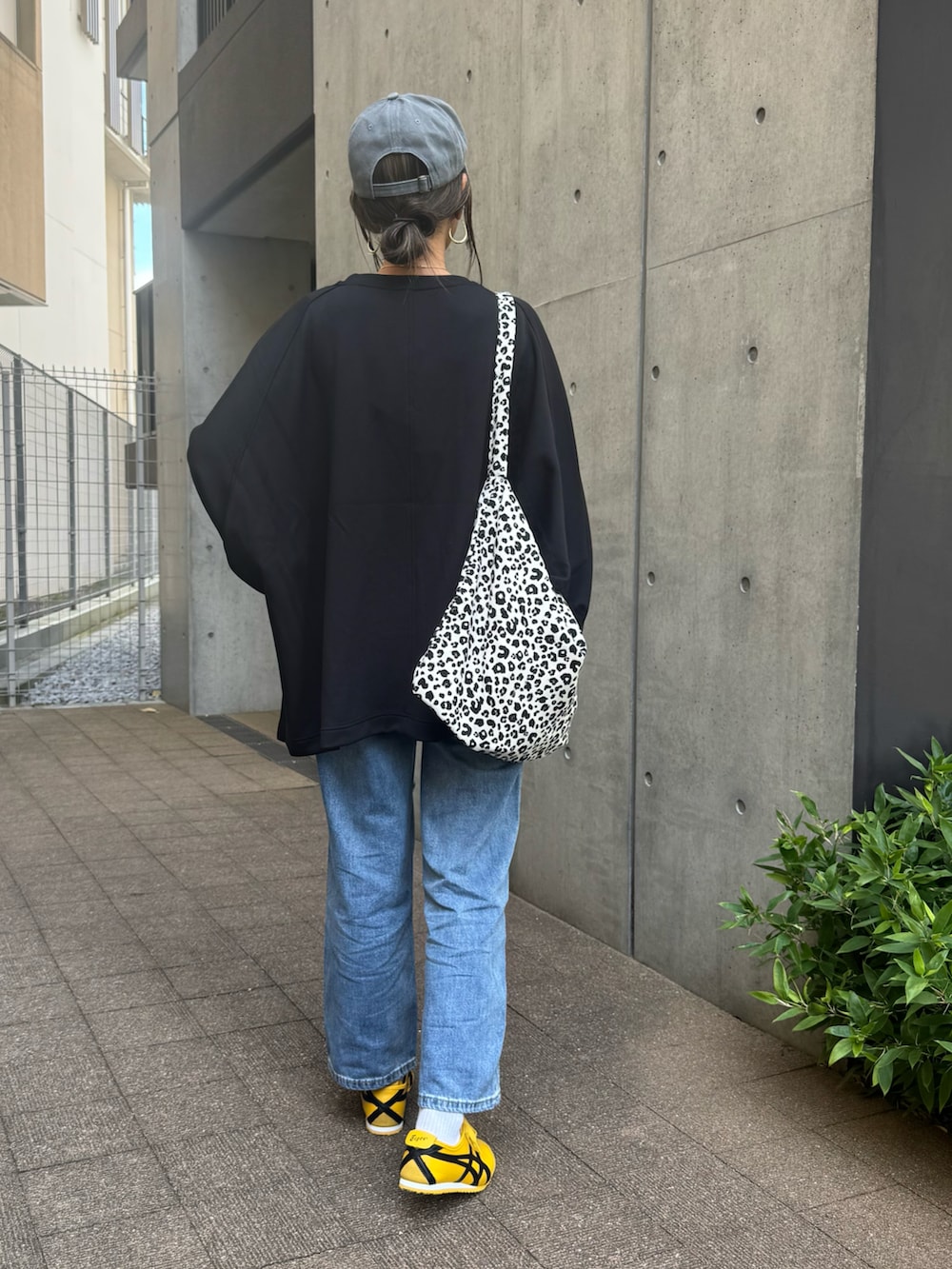 ブラック系のスウェット、ブルー系のデニムパンツ、ホワイト系のショルダーバッグを着用したレディースの秋コーディネートの3枚目の写真