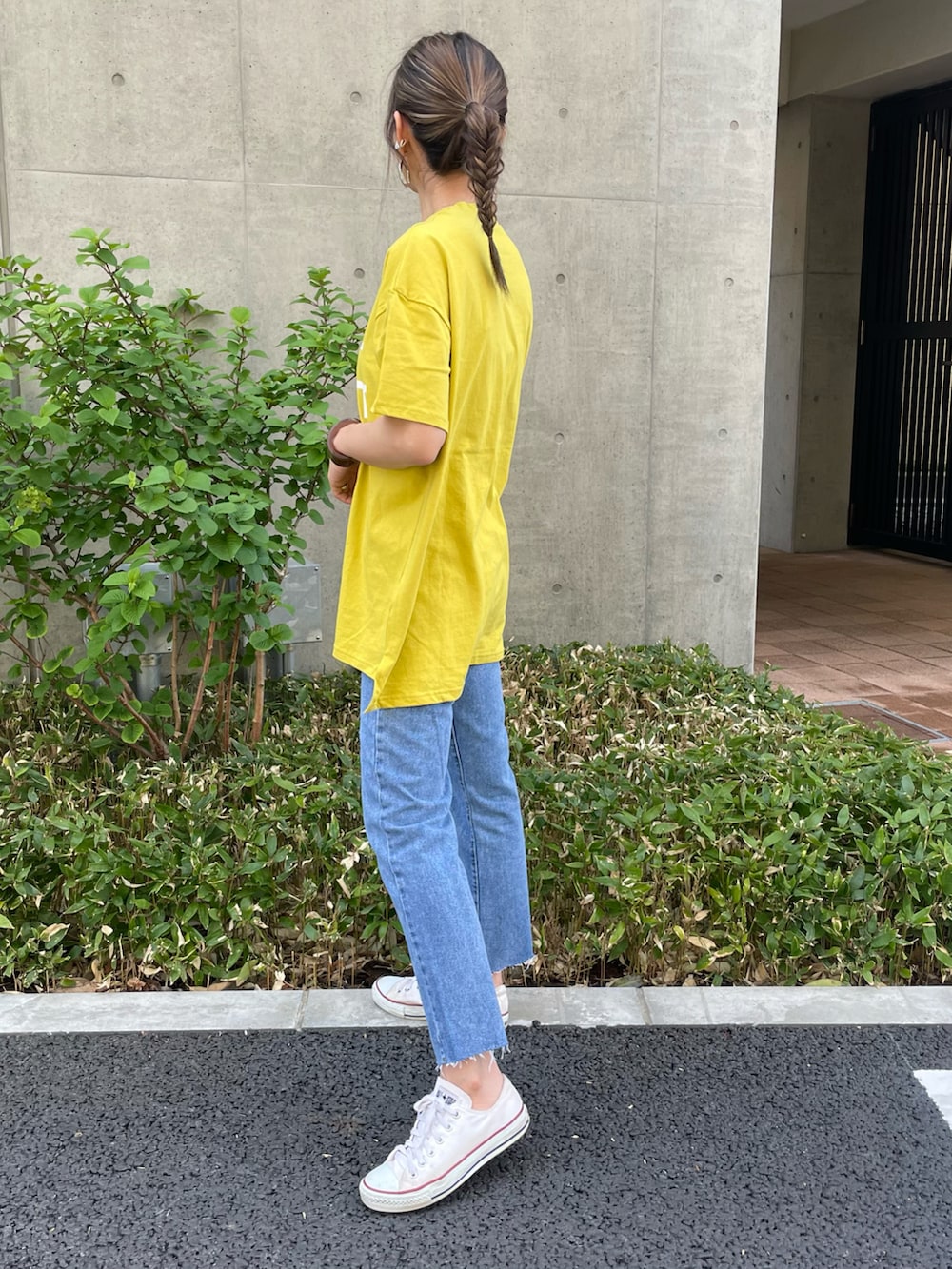 イエロー系のTシャツ/カットソー、ブルー系のデニムパンツ、ホワイト系のスニーカーを着用したレディースの春コーディネートの2枚目の写真