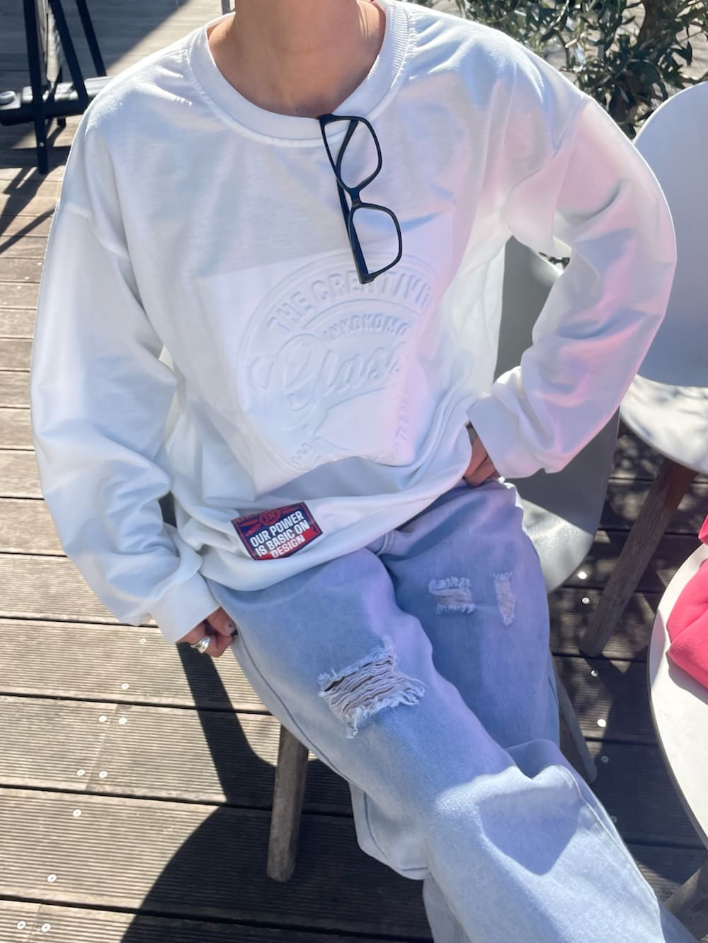 ホワイト系のスウェット、ブルー系のデニムパンツ、ピンク系のトートバッグを着用したレディースの春コーディネートの4枚目の写真