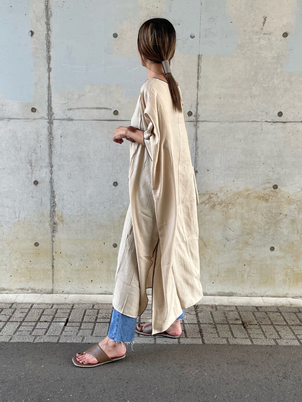 ベージュ系のワンピース、ブルー系のデニムパンツ、ブラウン系のサンダルを着用したレディースの夏コーディネートの2枚目の写真