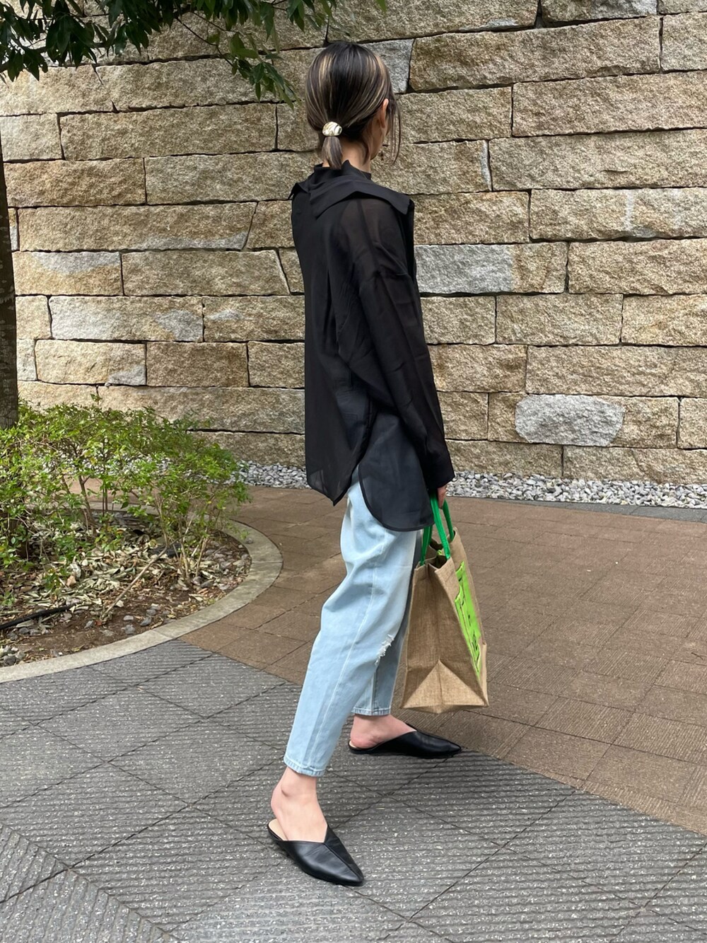 ブラック系のシャツ/ブラウス、ブルー系のデニムパンツ、グリーン系のトートバッグを着用したレディースの春コーディネートの2枚目の写真